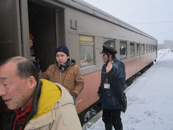 A conductor working for the Tsugaru Railway guiding passengers off the stove train at Kanagi Station.